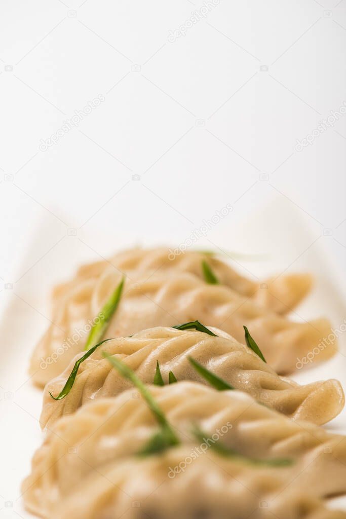 close up view of delicious Chinese boiled dumplings on plate near chopsticks on white background