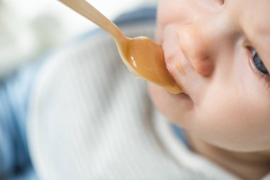 High angle view of baby boy during feeding fruit baby nutrition on white background