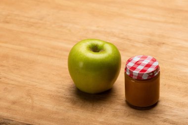 Jar of fruit baby nutrition with green apple on wooden background