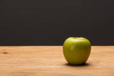 Green apple on wooden surface isolated on black  clipart