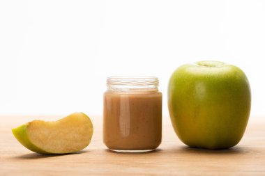 Green apple with fruit baby nutrition in jar on wooden surface isolated on white