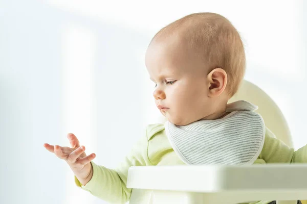 Bebê Olhando Para Mão Enquanto Sentado Cadeira Alimentação Fundo Branco — Fotografia de Stock