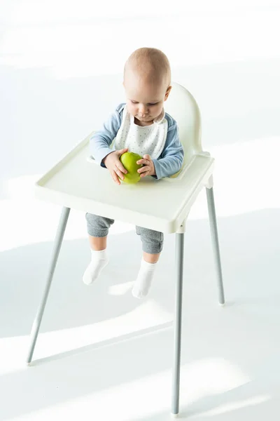 Cute Baby Holding Ripe Apple While Sitting Feeding Chair White — 스톡 사진