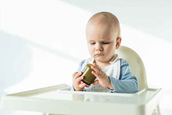 Foco Seletivo Bebê Bonito Segurando Frasco Comida Bebê Vegetal Cadeira — Fotografia de Stock