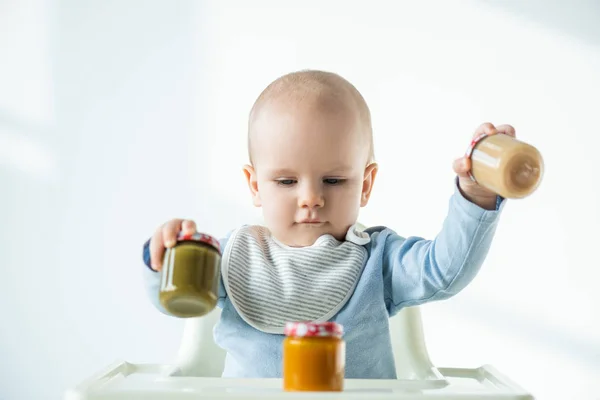 Foco Seletivo Bebê Segurando Frascos Nutrição Bebê Vegetal Enquanto Sentado — Fotografia de Stock