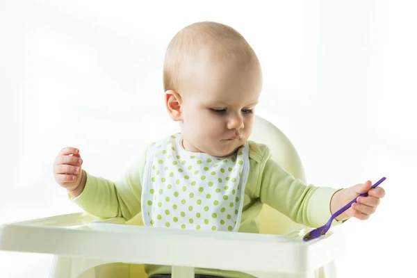 Bonito Bebê Segurando Colher Enquanto Sentado Cadeira Alimentação Fundo Branco — Fotografia de Stock
