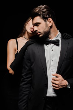 Eldivenli kadın, siyah giysili yakışıklı adamı kucaklıyor. 