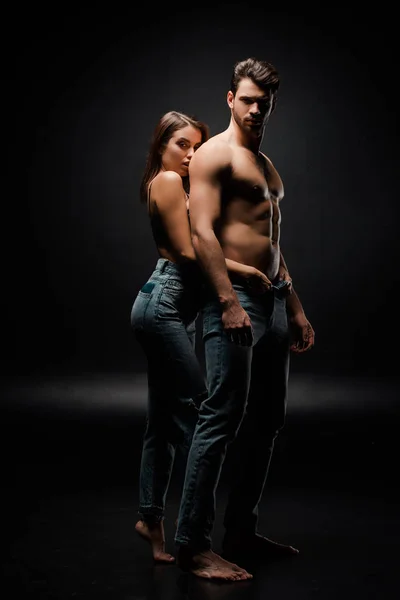 Attraktive Frau Berührt Jeans Eines Muskulösen Mannes Auf Schwarz — Stockfoto