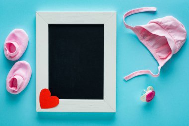 Mavi arka planda bebek şapkası, patik ve emzik olan boş karatahta manzarası, anneler günü konsepti 