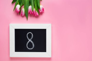 Pembe arka plandaki lalelerin yanında, tahtadaki 8 sayının üst görünümü