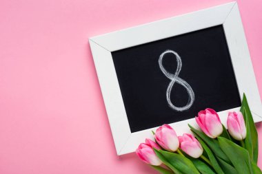 Top view of chalkboard with 8 number and tulips on pink surface clipart