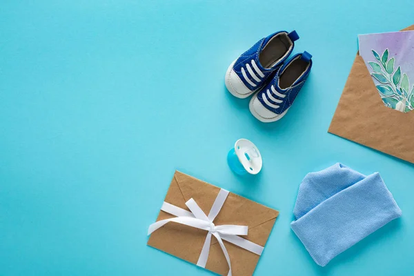 Top View Baby Booties Pacifier Envelopes Greeting Card Blue Background — Stock Photo, Image