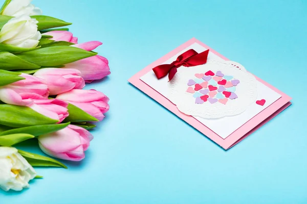 Bukiet Tulipanów Pobliżu Kartki Życzeniami Niebieskiej Powierzchni — Zdjęcie stockowe