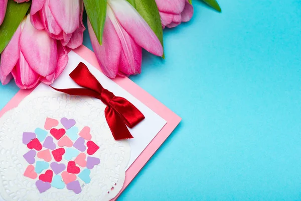 青い背景にグリーティングカードの近くにピンクのチューリップの花束の高い角度ビュー — ストック写真