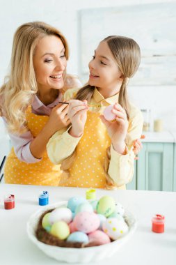 selective focus of happy kid holding easter egg and looking at mother 