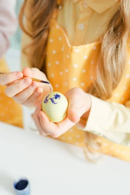 cropped view of kid painting easter egg 