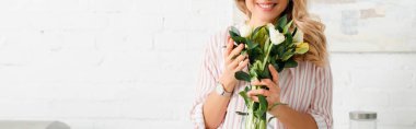 panoramic shot of happy woman holding bouquet of tulips 