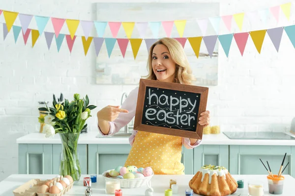 Cheerful Woman Pointing Finger Chalkboard Happy Easter Lettering — Stock Photo, Image