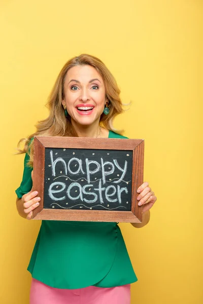 Smiling Woman Holding Chalkboard Happy Easter Lettering Isolated Yellow — 图库照片
