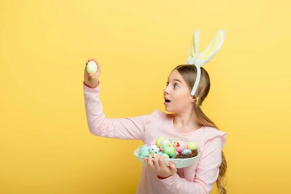 Überraschtes Kind Mit Hasenohren Das Osterei Isoliert Auf Gelb Betrachtet — Stockfoto
