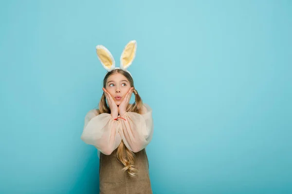 Surprised Kid Bunny Ears Touching Face Looking Away Isolated Blue — ストック写真