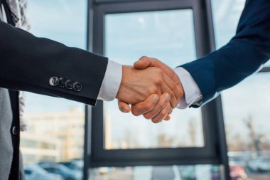 cropped view of businessmen shaking hands on meeting in office clipart
