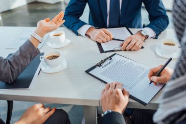 Profesyonel iş ortaklarının, kahve fincanlarıyla yapılan toplantıda sözleşme imzalamaları...