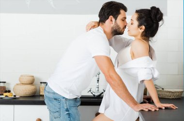 Bir erkeğin mutfakta seksi bir kadını sütyen ve tişörtle öptüğü görüntüler. 