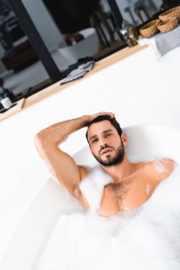 Yakışıklı adam banyo yaparken kameraya bakıyor. 