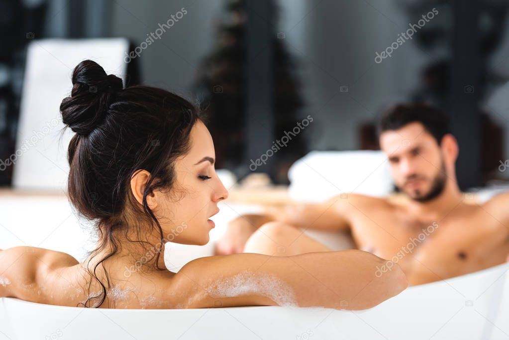Selective focus of sensual woman taking bath with handsome boyfriend in bathroom