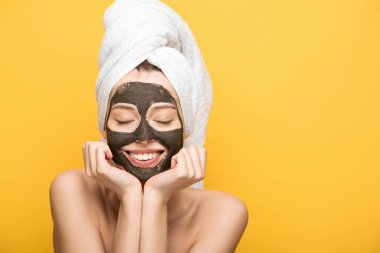 Yüzünde kilden maske ve havluyla neşeli bir kız. Yüzünün yanında el ele tutuşmuş, gözleri kapalı, sarıda izole edilmiş.