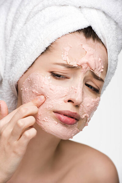 displeased girl with peeling facial mask touching face isolated on white