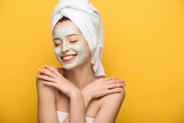 happy girl with nourishing facial mask hugging herself with closed eyes isolated on yellow