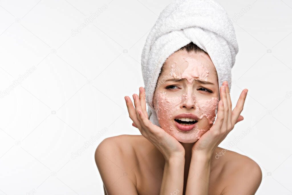 dissatisfied girl with peeling facial mask holding hands near face isolated on white