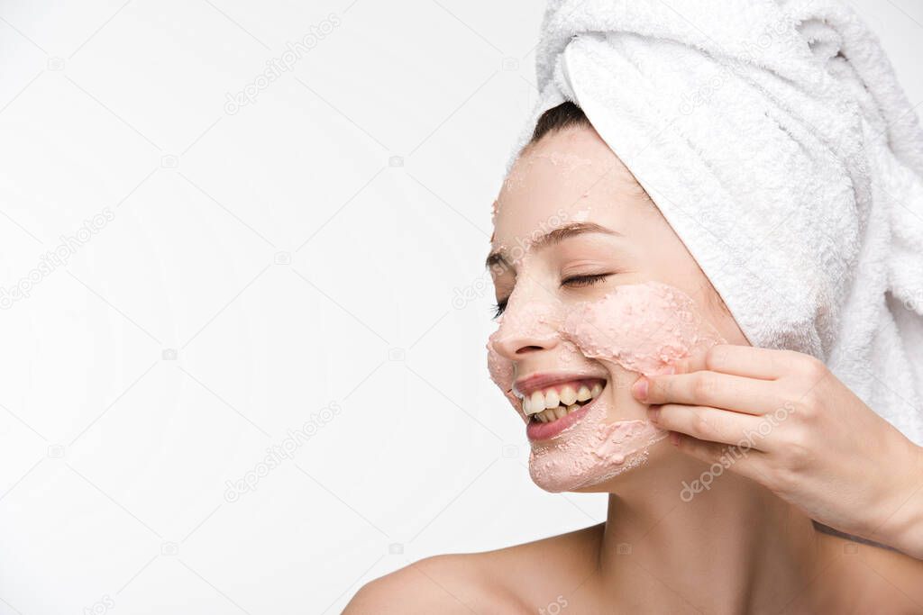 smiling girl with closed eyes removing peeling mask from face isolated on white