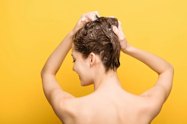 妇女用黄色背景的洗发水洗头的倒影 — 图库照片