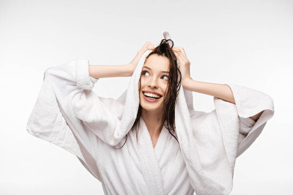 счастливая девушка вытирая влажные чистые волосы с белым махровым полотенцем, глядя в сторону изолированы на белом
