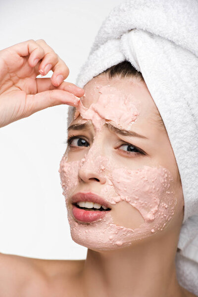 displeased girl removing scrab mask from face while looking at camera isolated on white