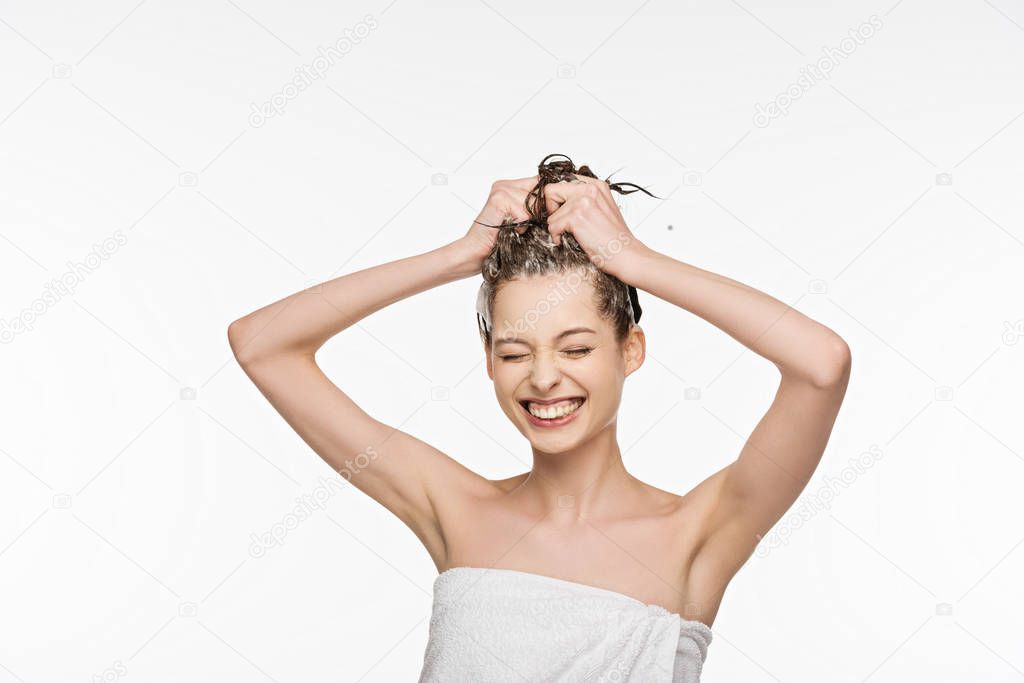 cheerful girl smiling with closed eyes while washing hair isolated on white