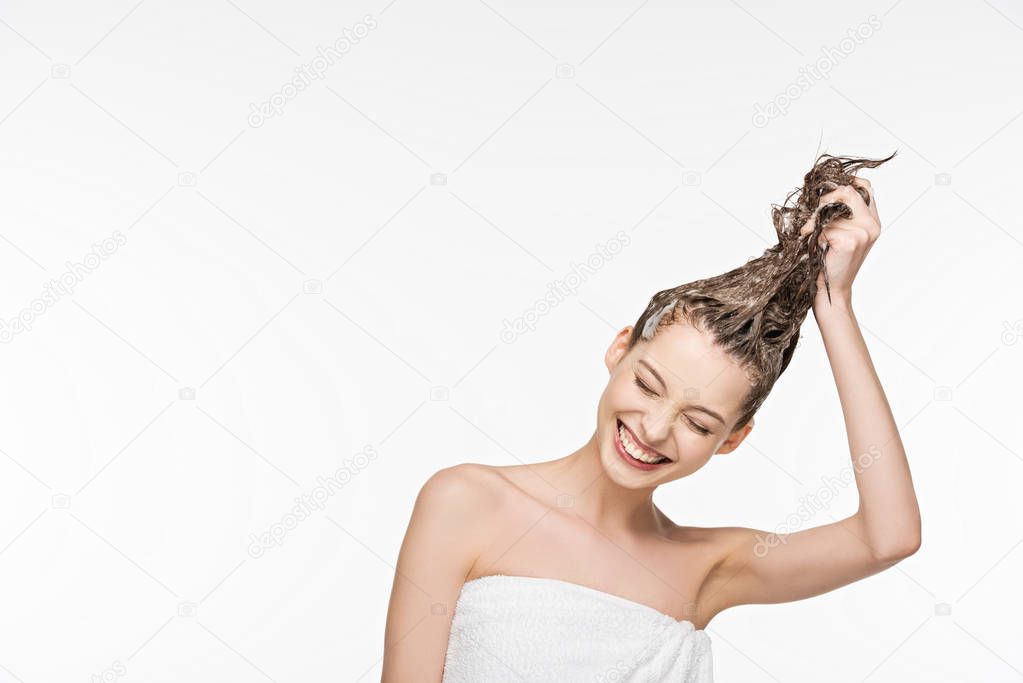 happy girl smiling with closed eyes while washing long hair isolated on white