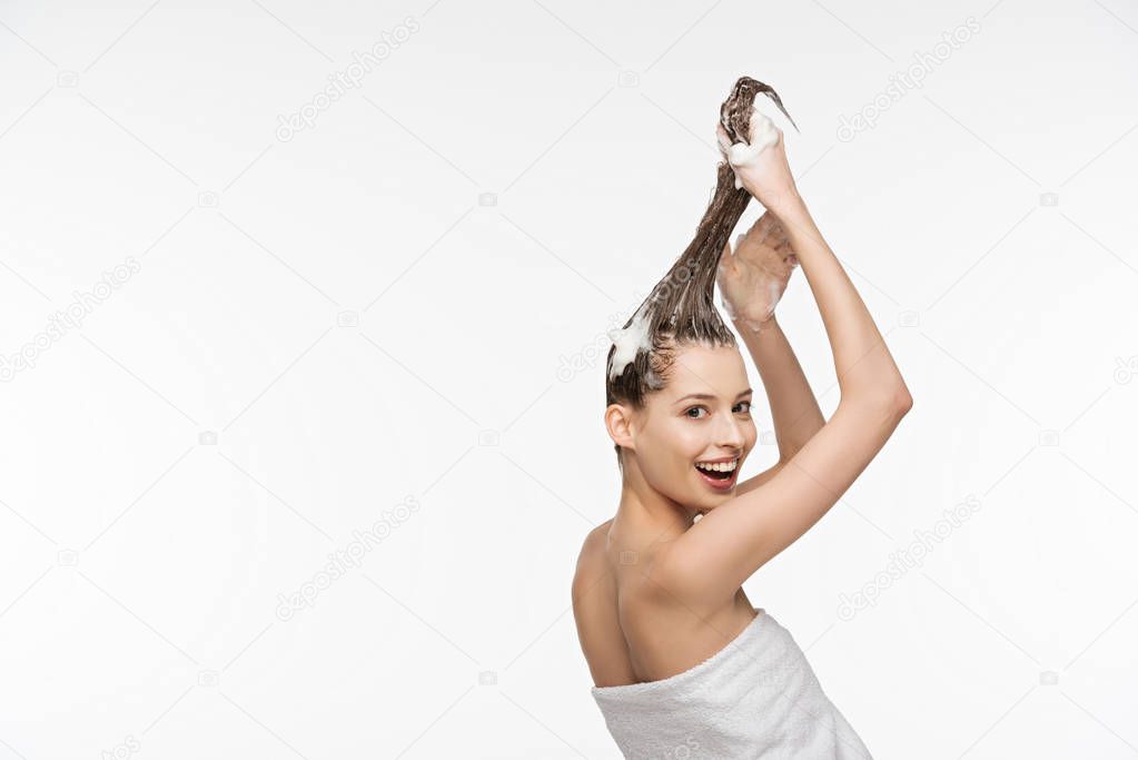 beautiful girl smiling at camera while washing long hair isolated on white 