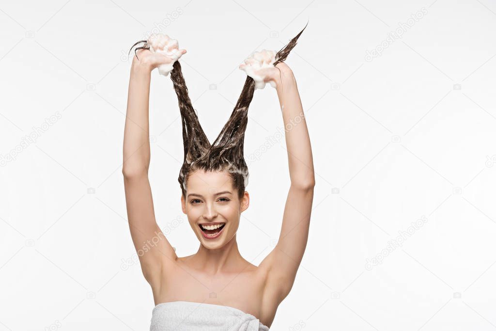 cheerful girl having fun while washing long hair isolated on white