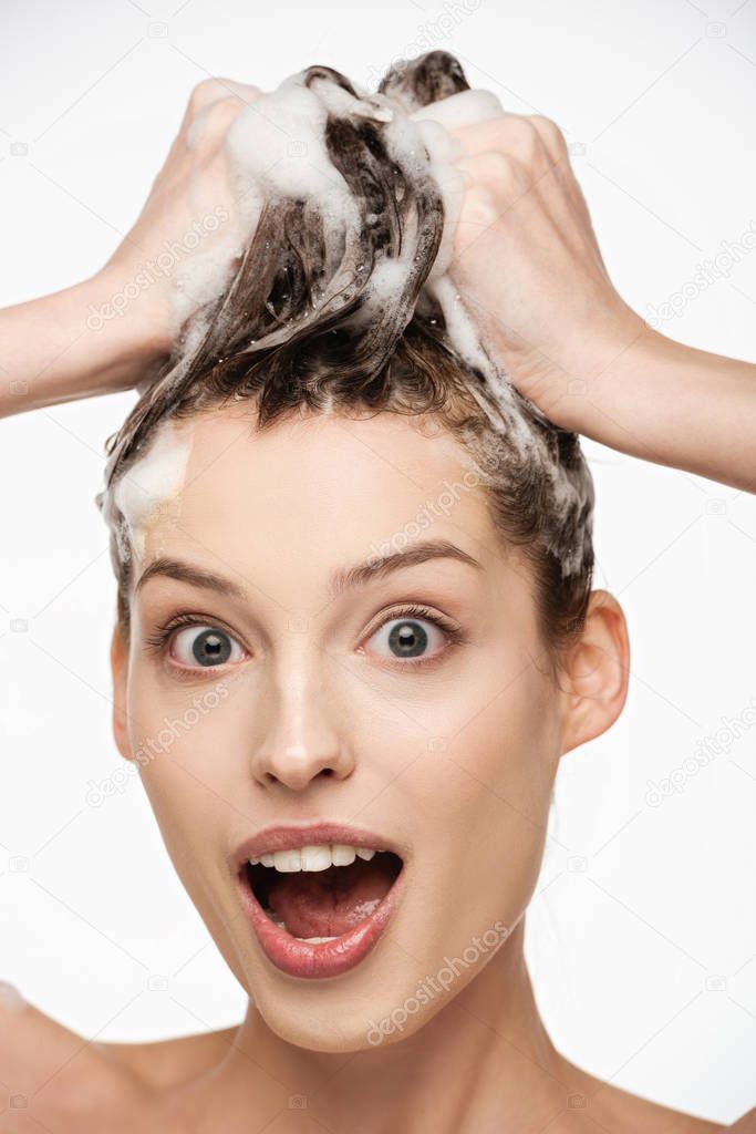 shocked girl with open mouth and wide open eyes washing hair isolated on white