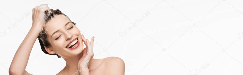 panoramic shot of happy girl washing hair while touching face isolated on white