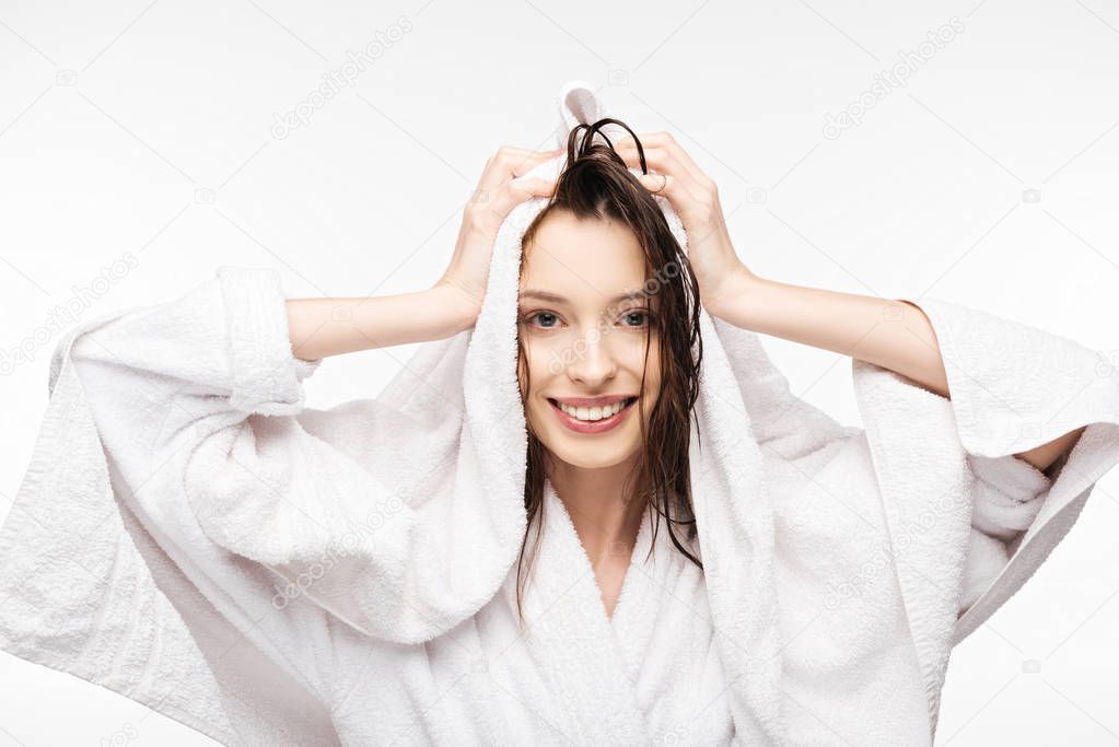 happy girl wiping wet clean hair with white terry towel while smiling at camera isolated on white