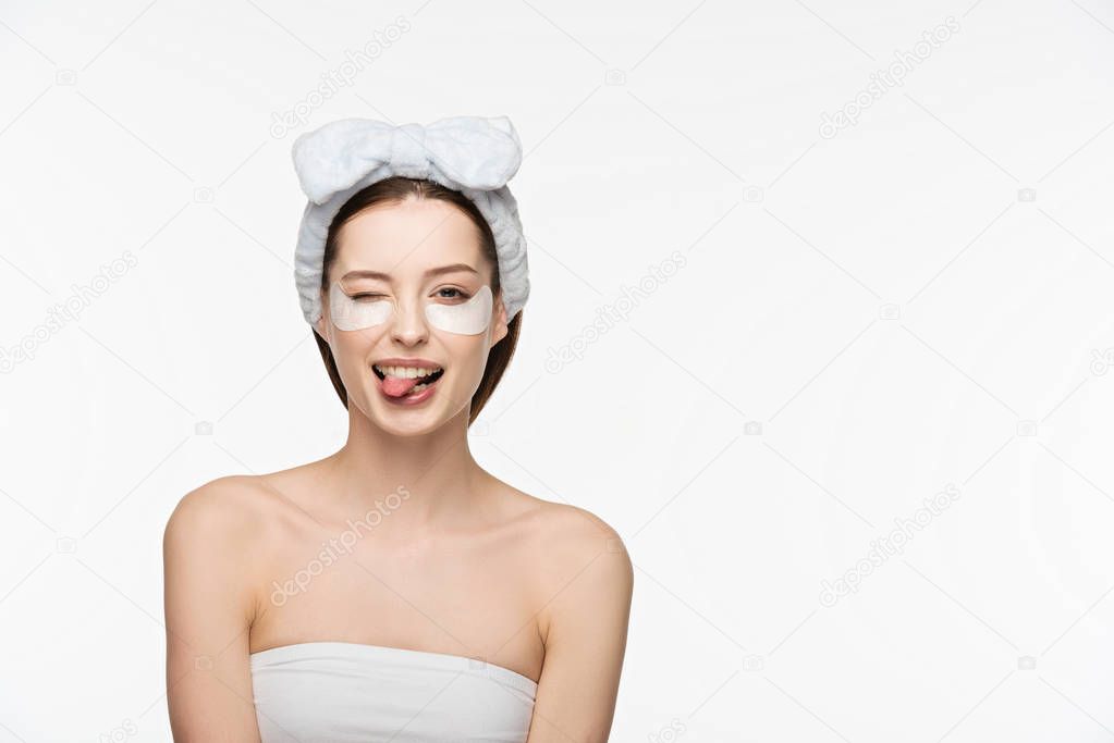 cheerful girl with eye patches winking and sticking out tongue while looking at camera isolated on white 