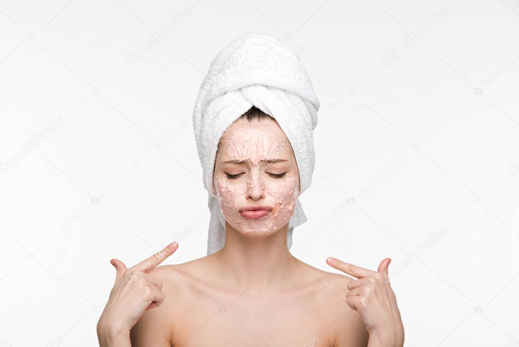 displeased pointing with fingers at peeling mask on face while standing with closed eyes isolated on white