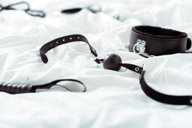 selective focus of bdsm leash and gag on white bedding  clipart
