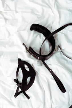 Bdsm tasma ve göz maskesi beyaz yatak üzerinde üst görünüm 