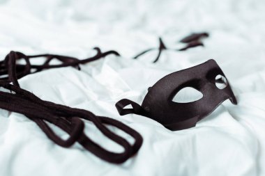 selective focus of eye mask and black rope on white bedding  clipart